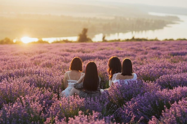 Grupo de mulheres jovens sentadas no campo de lavanda em dia de verão