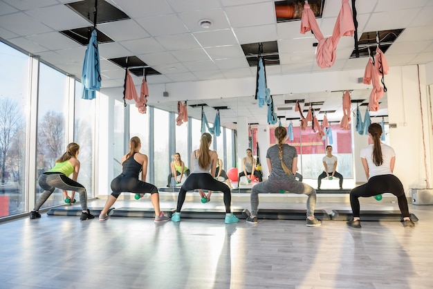 Foto grupo de mulheres jovens treinando na academia com halteres