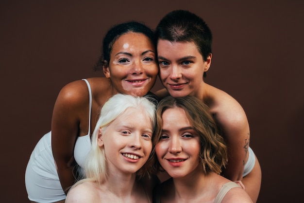 Grupo de mulheres multiétnicas com diferentes tipos de pele posando juntas em estúdio