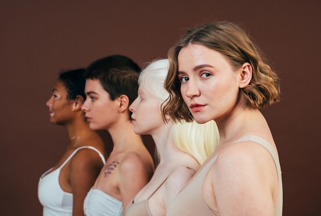 Grupo de mulheres multiétnicas com diferentes tipos de pele posando juntas em estúdio