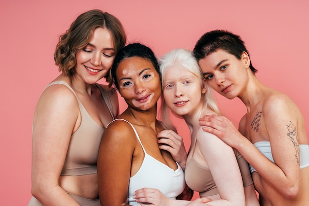 Grupo de mulheres multiétnicas com diferentes tipos de pele posando juntas em estúdio