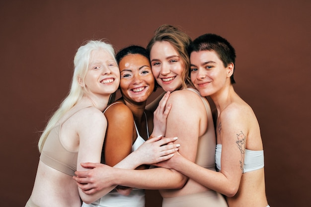 Grupo de mulheres multiétnicas com diferentes tipos de pele posando juntos no estúdio. conceito sobre positividade corporal e autoaceitação