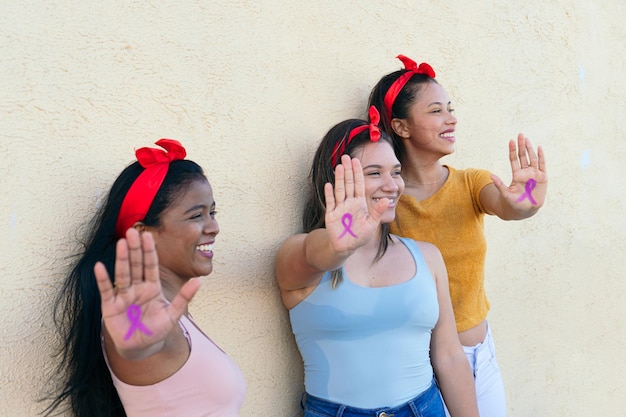 Grupo de mulheres multiétnicas mostrando as mãos com um desenho de fita rosa de conscientização sobre o câncer de mama Símbolo internacional do câncer de mama Conceito do dia internacional da mulher 39 e do dia mundial do câncer