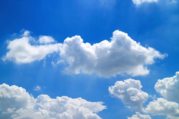 Grupo de nuvens cumulus fofas com feixe incrível fluindo no céu azul ensolarado