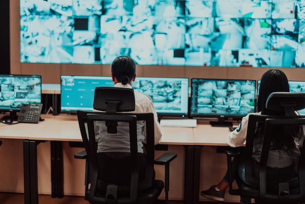 Grupo de operadores de centros de dados de segurança trabalhando em uma sala de monitoramento de CCTV olhando para vários monitores Oficials monitorando várias telas em busca de atividades suspeitas Equipe trabalhando no controle do sistema