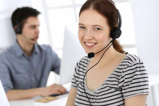 Foto grupo de operadores no trabalho call center foco na bela recepcionista no fone de ouvido