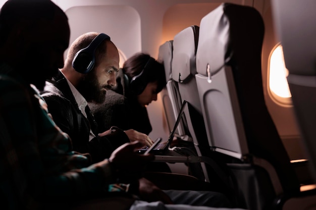 Grupo de passageiros viajando em voo comercial de jato, sentados antes de decolar. pessoas voando com avião no destino de férias internacionais, usando dispositivos modernos durante o pôr do sol.