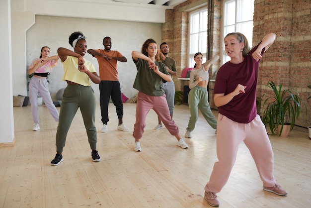 Grupo de pessoas aprendendo exercícios de dança com o instrutor no salão de dança