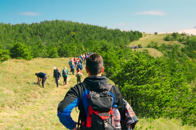 Foto grupo de pessoas caminhando e caminhadas na colina verde montanha. estilo de vida ativo e bu de equipe