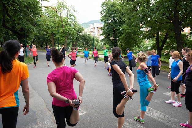 grupo de pessoas correndo alongamento no parque antes do treino