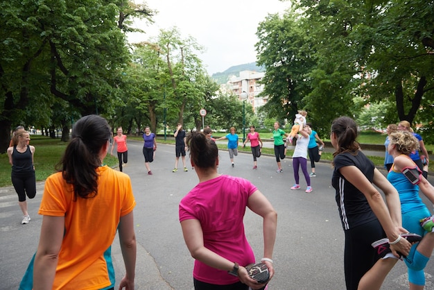 grupo de pessoas correndo alongamento no parque antes do treino