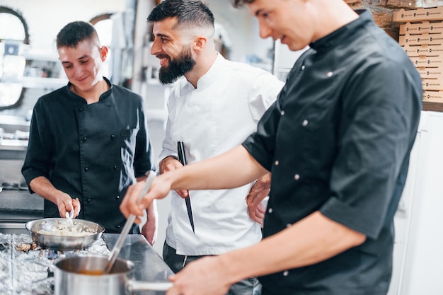 Grupo de pessoas cozinhando comida na cozinha juntos Dia ocupado no trabalho