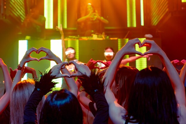 Foto grupo de pessoas dançando na discoteca ao som da música do dj no palco