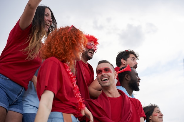 Grupo de pessoas de diferentes raças animando seu time no estádio de futebol