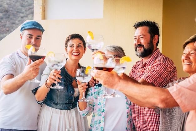 Foto grupo de pessoas de idades variadas de caucasianos se divertindo juntos celebrando um evento bebendo coquetel com vinho tinto de vodka branca