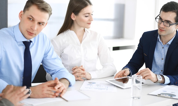 Grupo de pessoas de negócios discutindo questões em uma reunião em um escritório moderno. Gerentes em negociação ou brainstorming. Trabalho em equipe, parceria e conceito de negócio