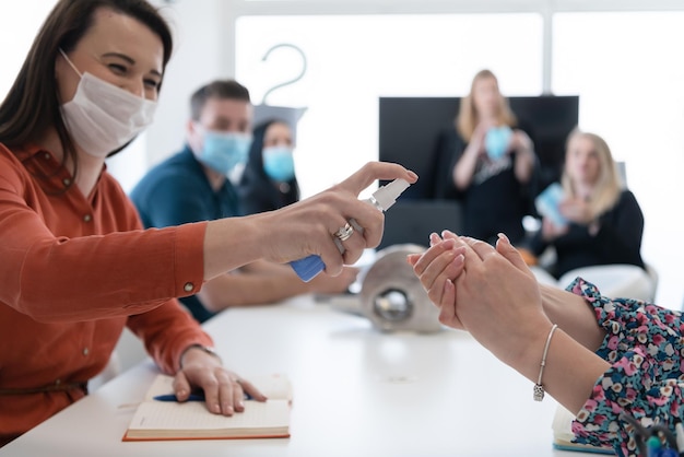 grupo de pessoas de negócios em reunião usando desinfetante para as mãos antibacteriano para prevenir a pandemia de coronavírus novo conceito de surto covid19 normal