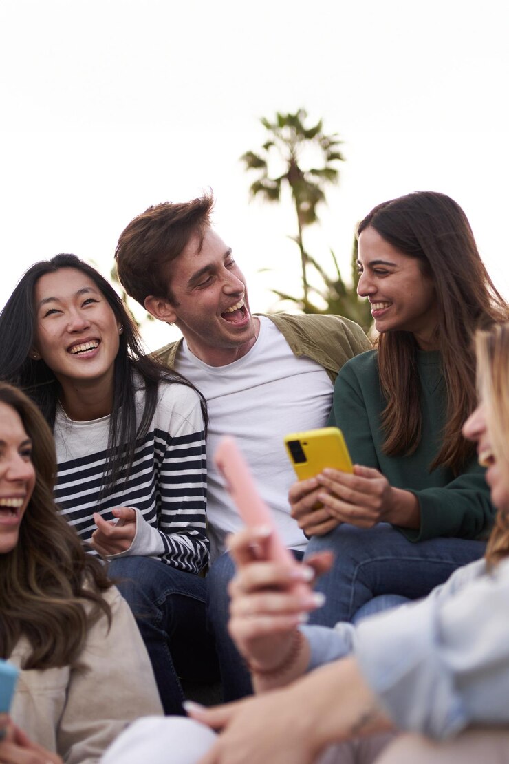 Foto grupo de pessoas diversas a desfrutar do dia juntos ao ar livre com telemóveis na mão jovens amigos multirraciais