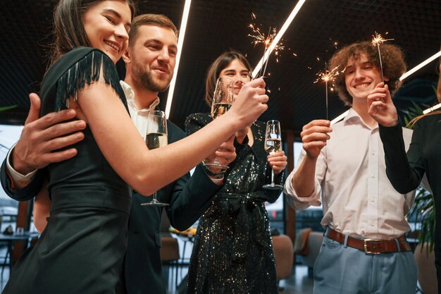 Grupo de pessoas em roupas bonitas e elegantes estão comemorando o Ano Novo dentro de casa juntos