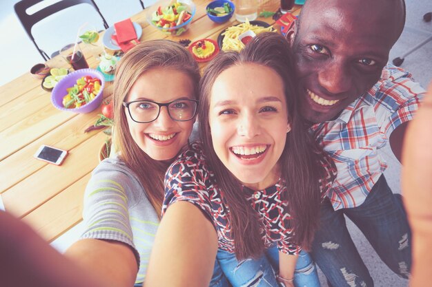 Grupo de pessoas fazendo selfie durante o almoço Amigos próprios amigos são fotografados para comer