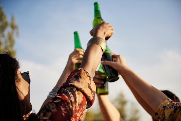 Grupo de pessoas fazendo um brinde de comemoração com garrafas de cerveja