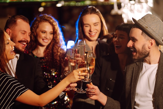 Grupo de pessoas felizes segurando estrelinhas na festa. Jovens amigos tilintando taças de champanhe.