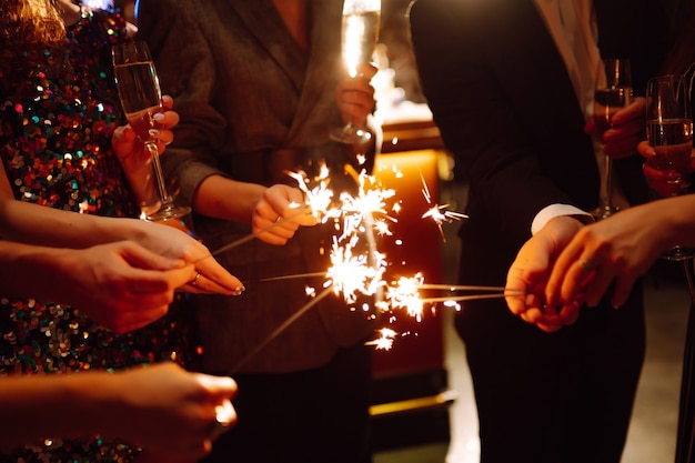 Grupo de pessoas felizes segurando estrelinhas na festa. Jovens amigos tilintando taças de champanhe.