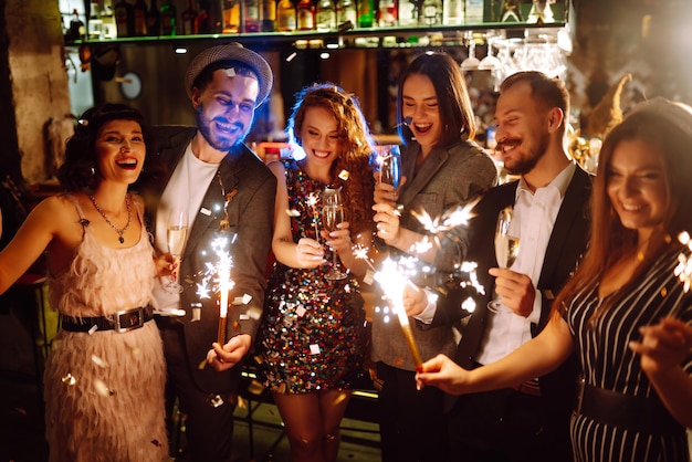 Foto grupo de pessoas felizes segurando estrelinhas na festa. jovens amigos tilintando taças de champanhe.