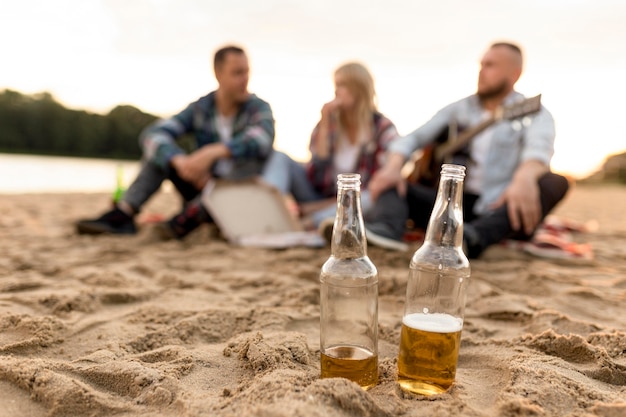Foto grupo de pessoas fora de foco com duas garrafas de cerveja