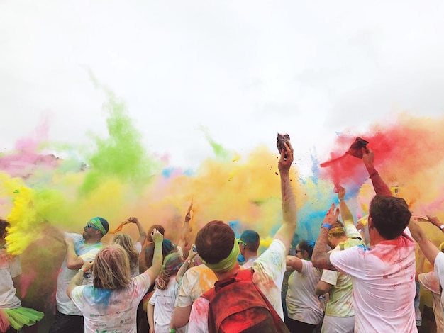 Grupo de pessoas jogando holi com tintas em pó coloridas contra o céu claro