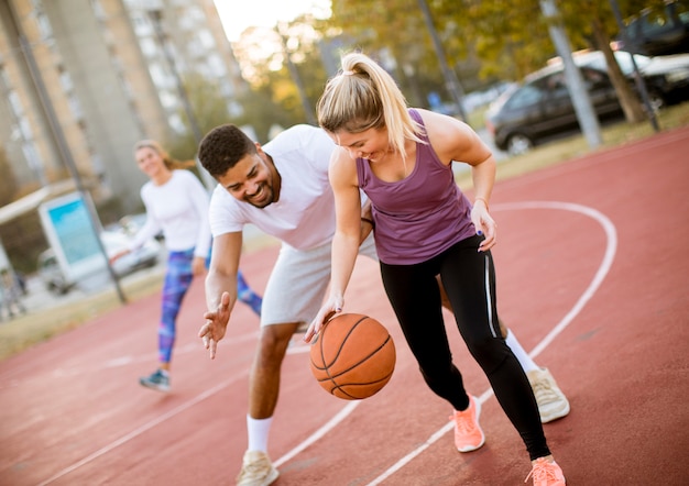 Grupo de pessoas multiétnicas jogando basquete na quadra