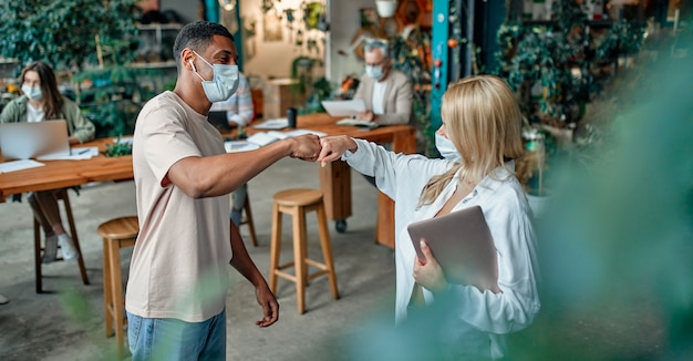 Foto grupo de pessoas multirraciais, trabalhando em um escritório moderno durante o coronavírus. jovens empresários e o chefe sênior estão trabalhando juntos usando máscaras de proteção facial. medidas preventivas durante covid-19