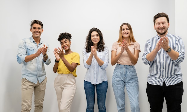 Foto grupo de pessoas na fila aplaude, colegas de trabalho, jovens multiétnicos,