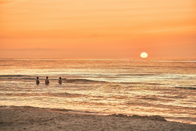 Grupo de pessoas no oceano durante o pôr-do-sol Grupo diversificado Desfrutando das águas serenas