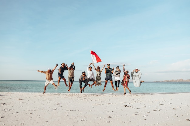 Grupo de pessoas pulando juntas na praia para comemorar o Dia da Independência da Indonésia