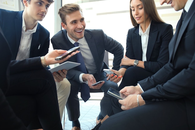 Grupo de pessoas que usam telefones inteligentes, sentado na reunião.