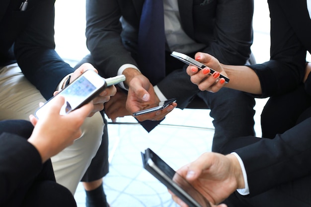 Grupo de pessoas que usam telefones inteligentes, sentado na reunião.