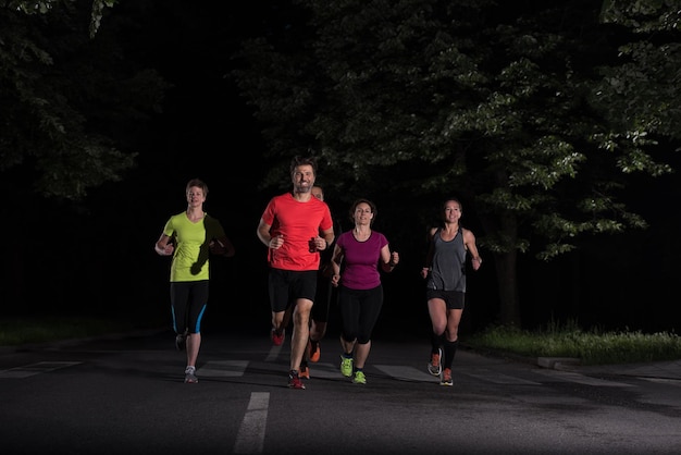 grupo de pessoas saudáveis, movimentando-se no parque da cidade, equipe de corredores no treinamento de noite