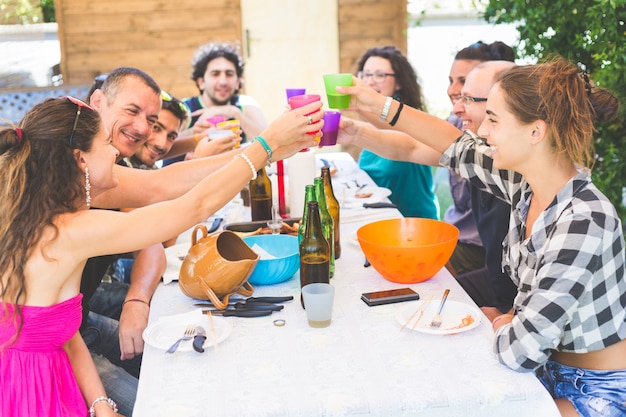 Grupo de pessoas sentadas almoçando juntos e brindando