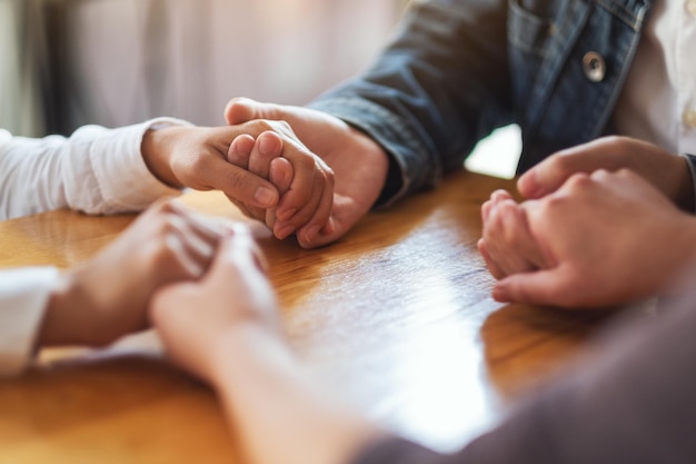 Grupo de pessoas sentadas em círculo de mãos dadas e orando juntas ou em sessão de terapia