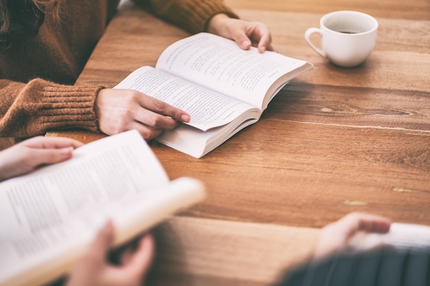 Foto grupo de pessoas sentado e lendo livros juntos na mesa de madeira