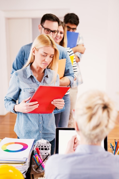 Grupo de pessoas trazendo relatórios de trabalho para o chefe deles.