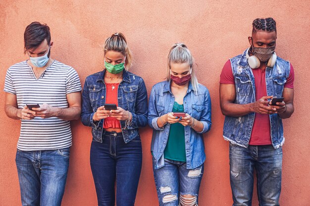 Grupo de pessoas usando seus smartphones em covid-19 vezes protegido com máscara facial