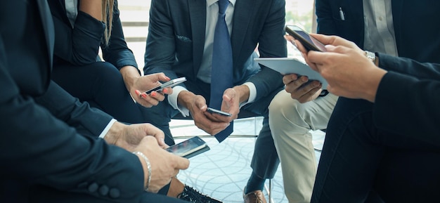 Grupo de pessoas usando telefones inteligentes sentados na reunião