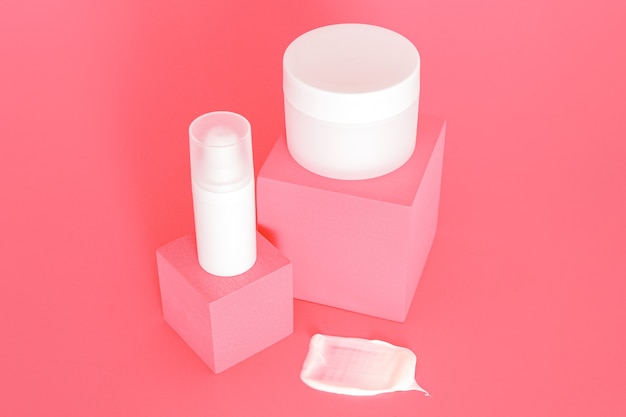 Grupo de potes de creme cosmético sem marca branca em pé em pódios cor de rosa. Apresentação do produto para cuidados da pele no fundo rosa. Maquete da moda. Cuidados com a pele, beleza e spa.