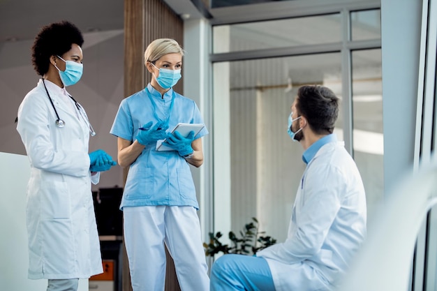 Grupo de profissionais de saúde usando máscaras enquanto se comunicam em um corredor do hospital