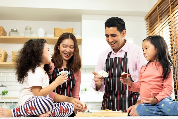 Grupo de quatro famílias diversas asiáticas e árabes pré-escolar criança árabe africana faz bolo cozinhando na cozinha pai mãe prepara decoração bonita com diversão educar bagunça de creme sobre o espaço da cópia do rosto