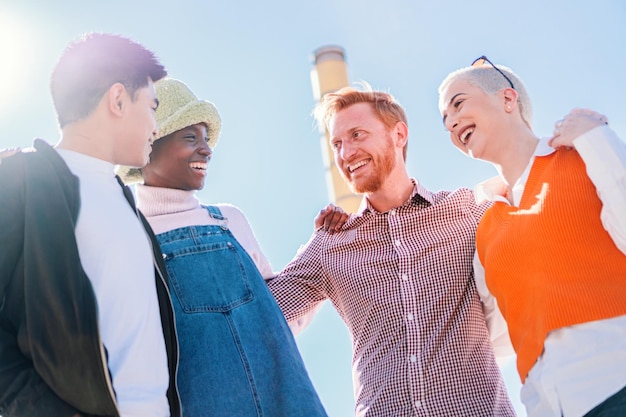 Grupo de quatro jovens amigos diversos se divertindo e sorrindo ao ar livre