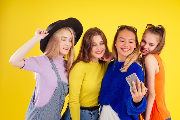 grupo de quatro meninas rindo tendo estúdio de fundo amarelo estilo festa de verão