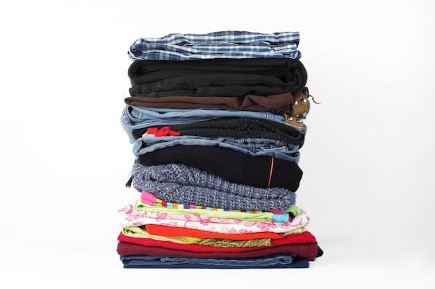 Grupo de roupas e acessórios empilha a pilha de fundo branco de jeans coloridos